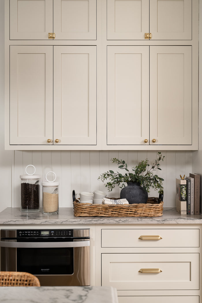 A large, round, weathered gray clay vase with a narrow neck styled with greenery on a kitchen counter. | Wildwood Home Co.