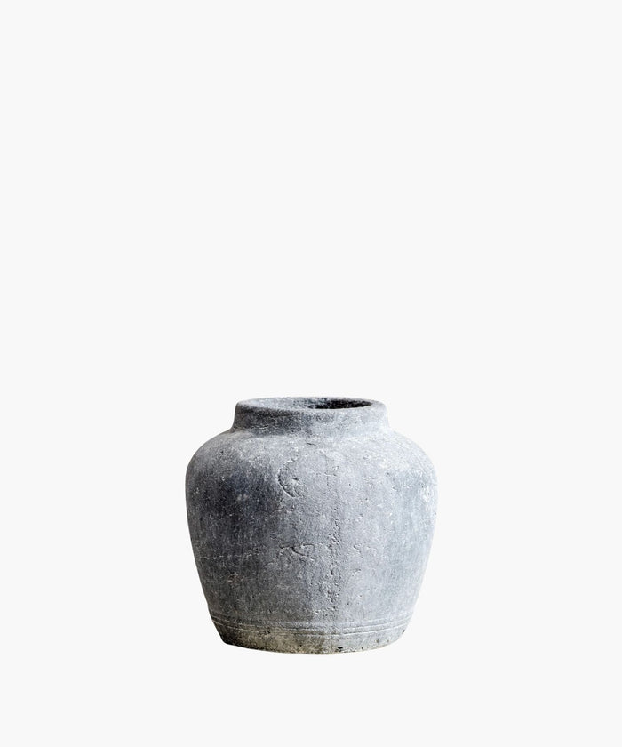 A rustic, gray stone vase with a round body and narrow neck against a white background. The textured surface and simple design suggest an ancient, timeless quality. | Wildwood Home Co.