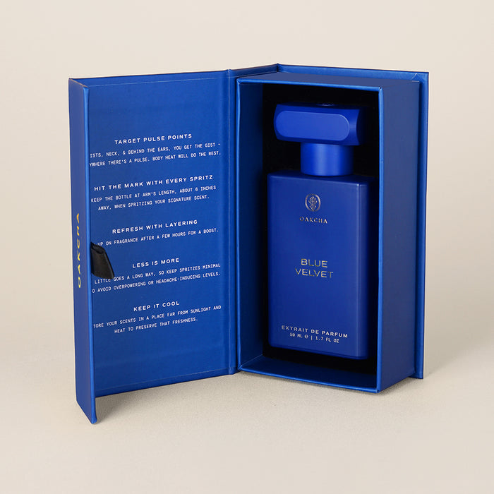 Angled front view of Blue Velvet perfume bottle in open blue presentation box showcasing the cobalt blue bottle against a beige background