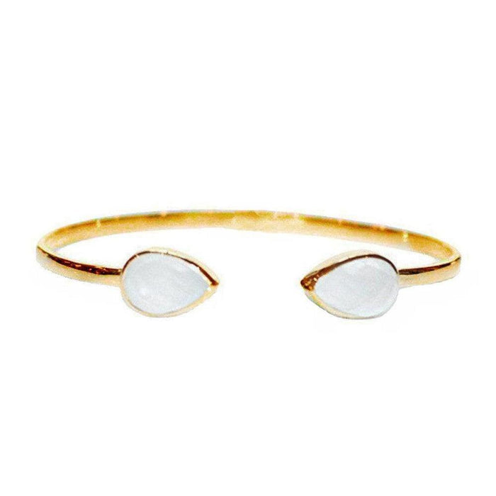 Gold cuff bracelet with two teardrop-shaped white stones.
