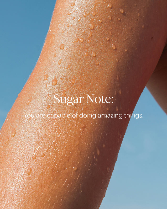 Close-up of a person's arm with water droplets against a blue sky, featuring the text 'Sugar Note: You are capable of doing amazing things.'.